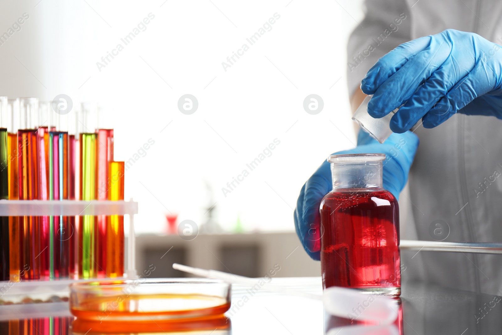 Photo of Scientist working at table with glassware in laboratory, closeup. Solution chemistry