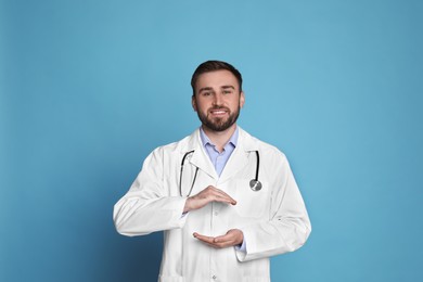 Photo of Young doctor holding something on light blue background