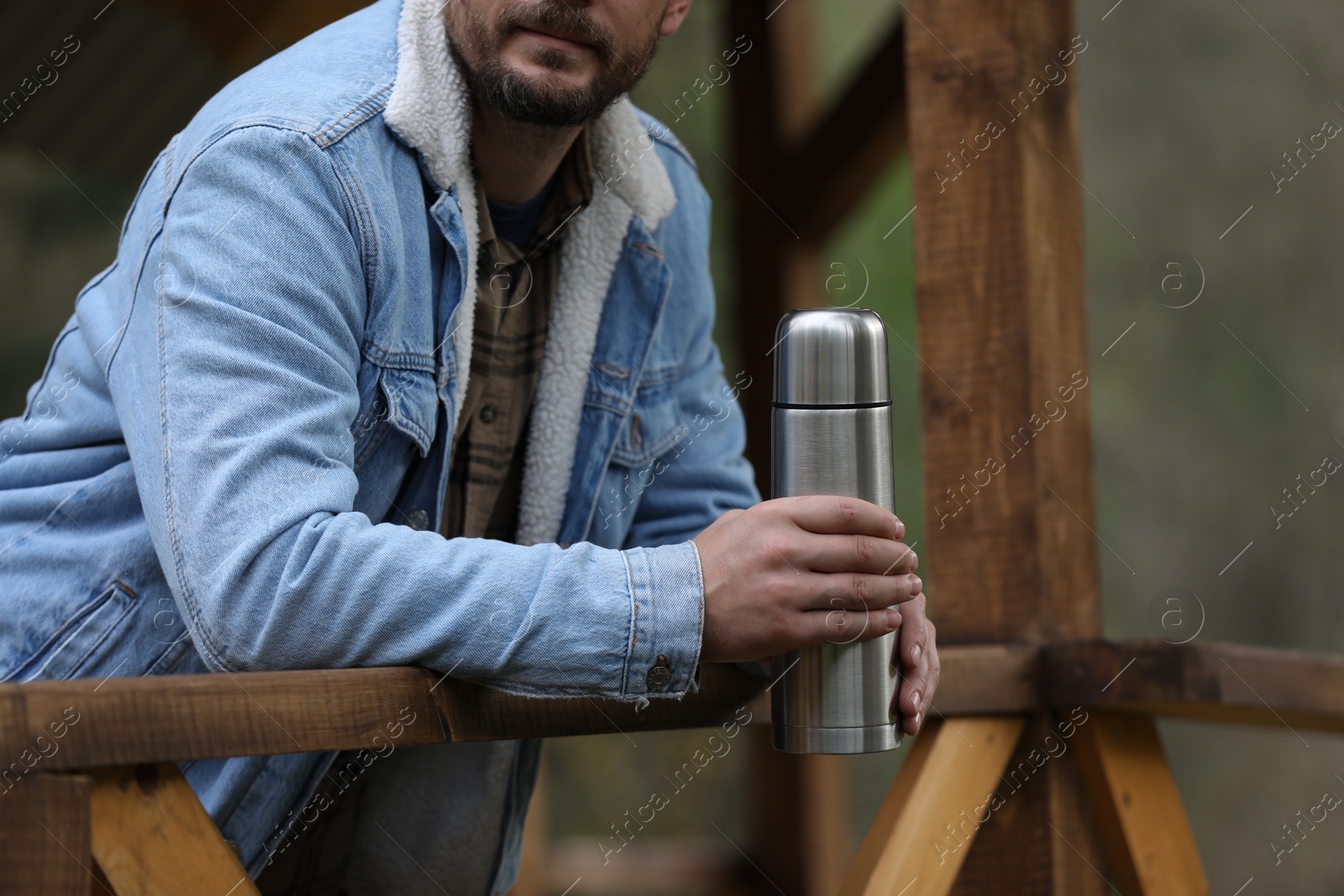 Photo of Man with metallic thermos outdoors, closeup view