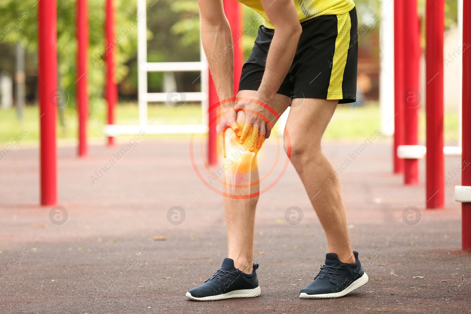 Image of Young man suffering from knee pain on sports ground, closeup