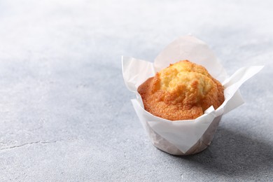 Photo of Delicious sweet muffin on grey textured table, space for text