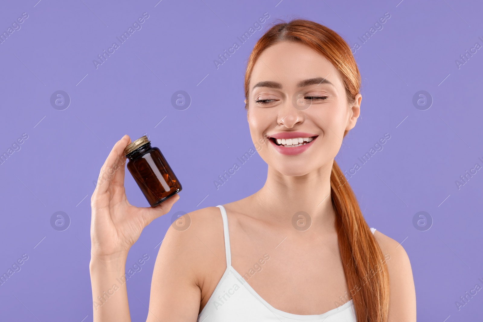 Photo of Happy young woman with bottle of pills on purple background. Weight loss