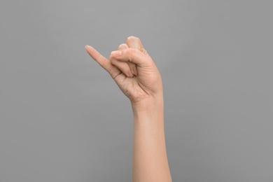 Photo of Woman showing J letter on grey background, closeup. Sign language