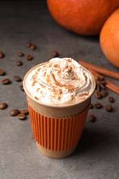 Photo of Paper cup with tasty pumpkin spice latte on gray table