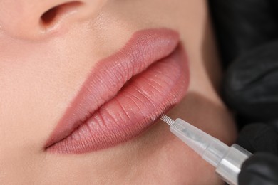 Photo of Young woman during procedure of permanent lip makeup in beauty salon, closeup