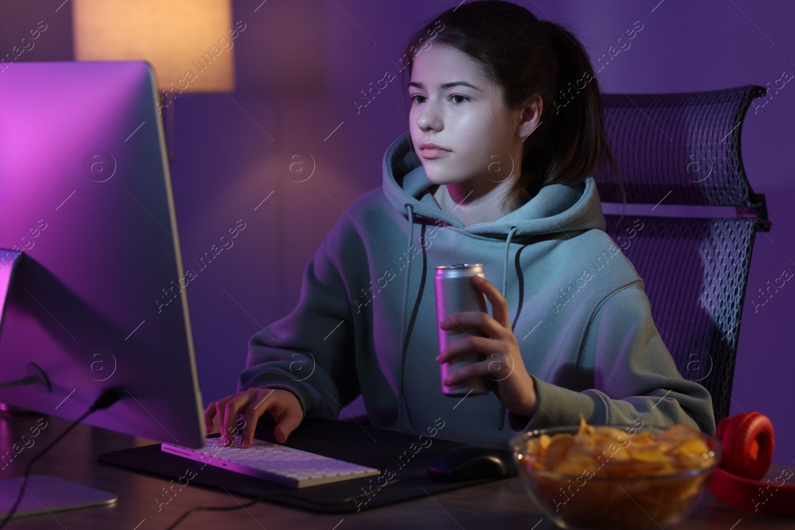 Photo of Girl with energy drink playing computer game at table in room