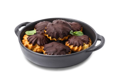 Photo of Delicious profiteroles with chocolate spread and mint in frying pan isolated on white