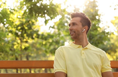 Photo of Young man with wireless earphones in park