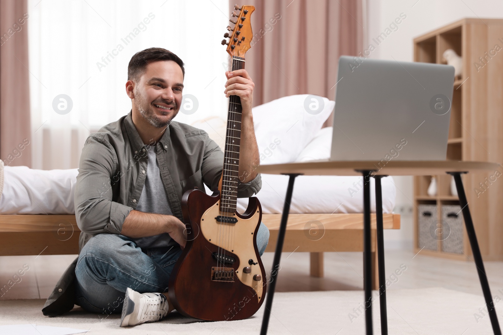 Photo of Music teacher with guitar conducting online lesson at home. Time for hobby