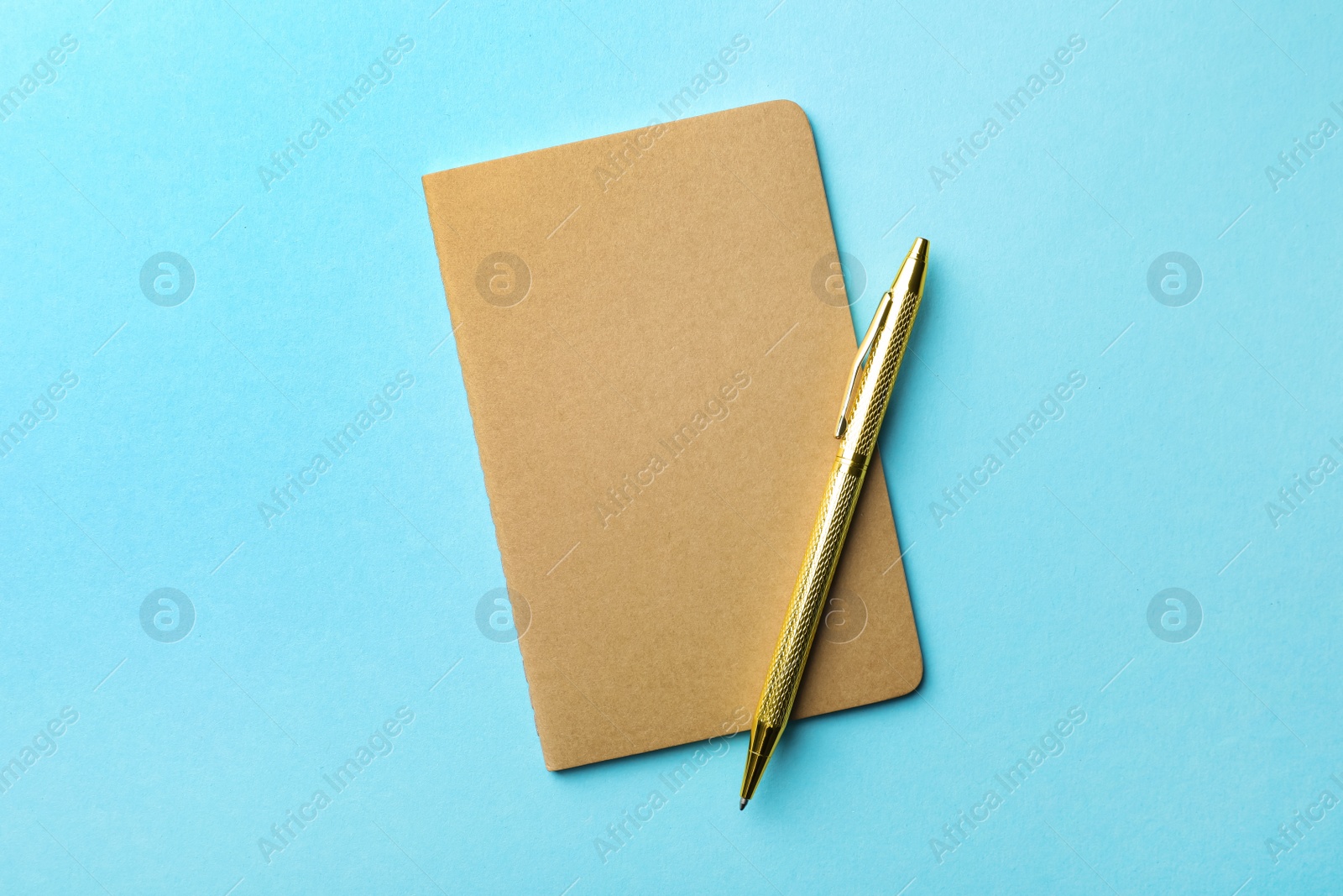 Photo of Stylish kraft planner with pen on light blue background, top view