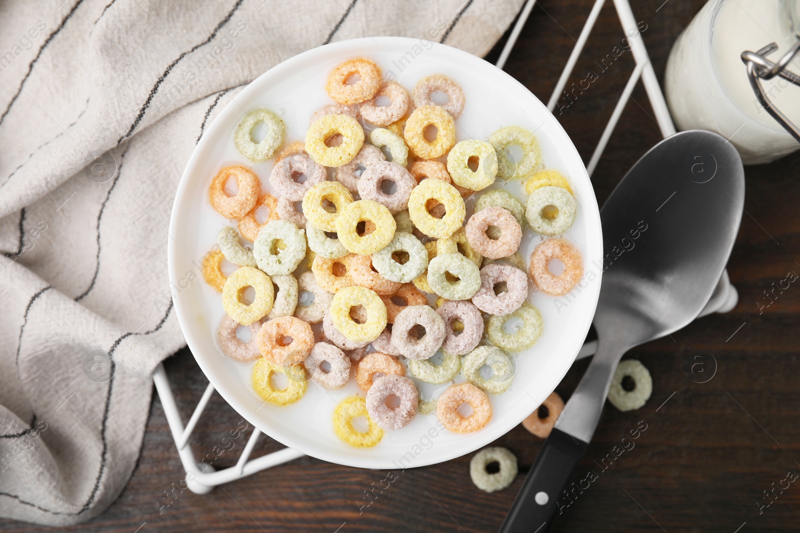 Photo of Cereal rings and milk in bowl on wooden table, top view