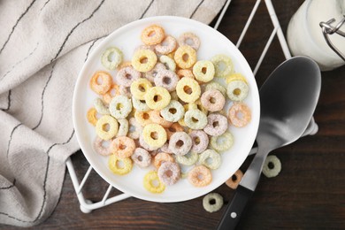 Photo of Cereal rings and milk in bowl on wooden table, top view