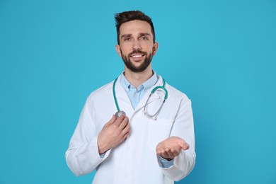 Photo of Doctor with stethoscope holding something on light blue background. Cardiology concept