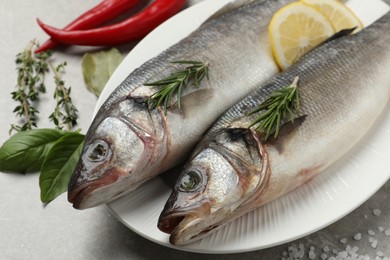 Photo of Sea bass fish and ingredients on grey table, closeup