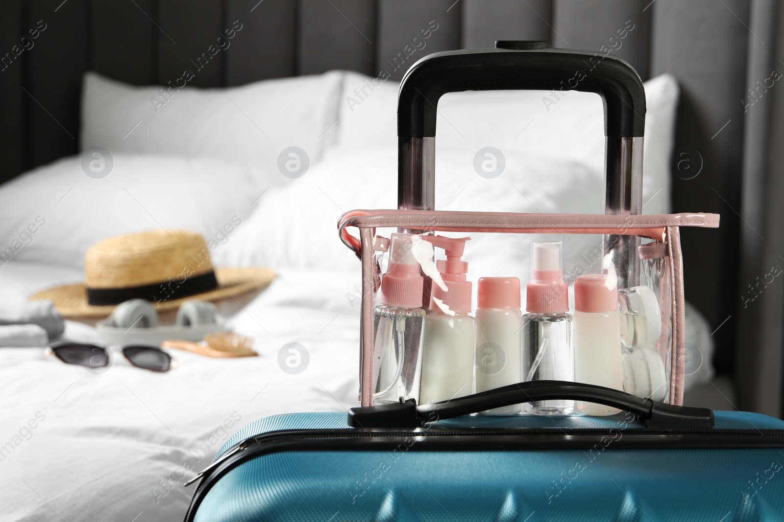 Photo of Cosmetic travel kit. Plastic bag with small containers of personal care products on suitcase in bedroom, space for text