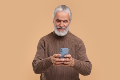 Photo of Senior man using smartphone on beige background