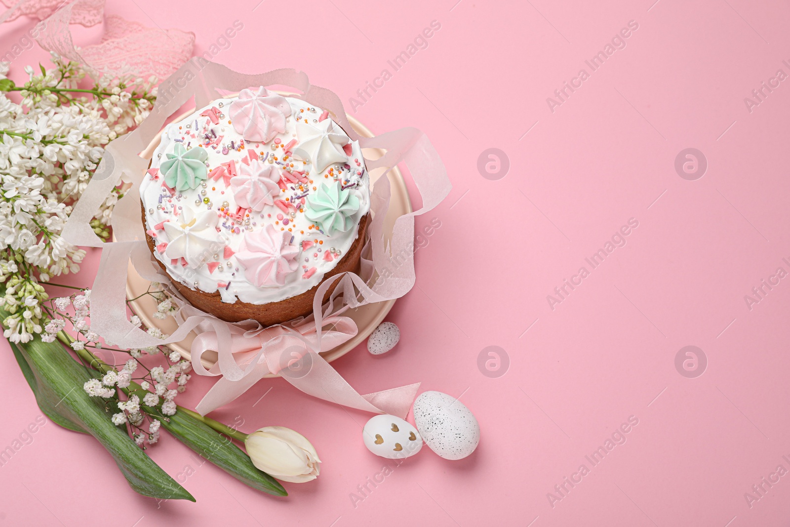 Photo of Traditional Easter cake with meringues and painted eggs on pink background, above view. Space for text