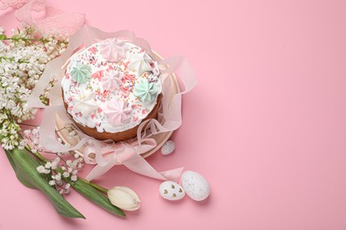 Traditional Easter cake with meringues and painted eggs on pink background, above view. Space for text