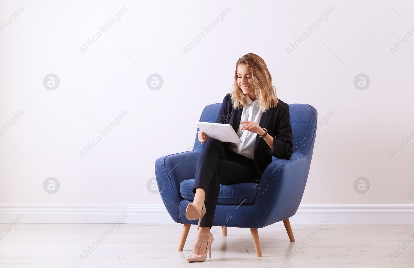 Photo of Young woman with tablet sitting in armchair indoors