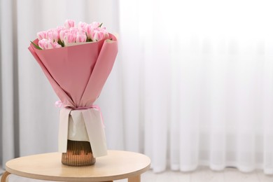 Photo of Beautiful bouquet of fresh pink tulips on table indoors. Space for text