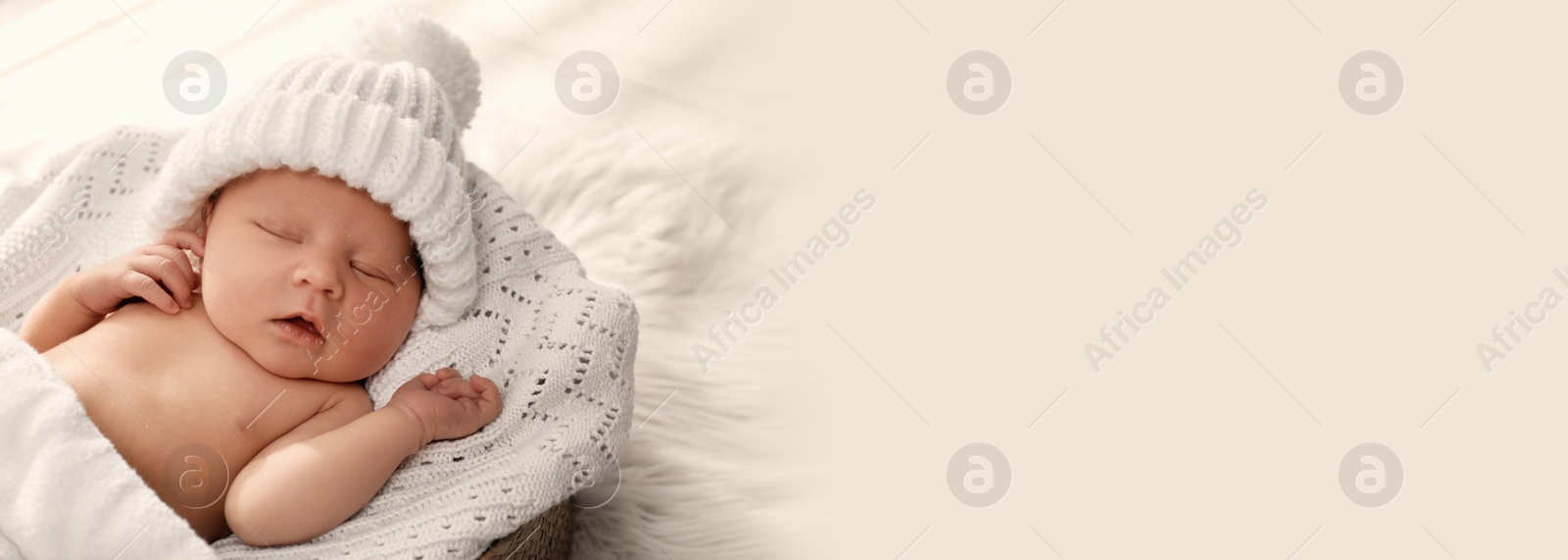 Image of Cute newborn baby in warm hat sleeping on knitted blanket, space for text. Banner design