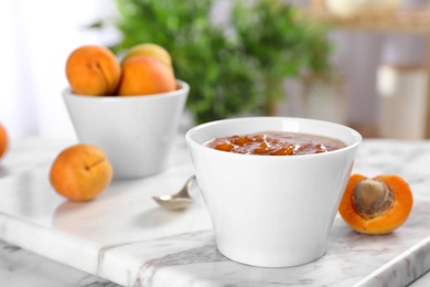 Photo of Bowl with tasty apricot jam on table