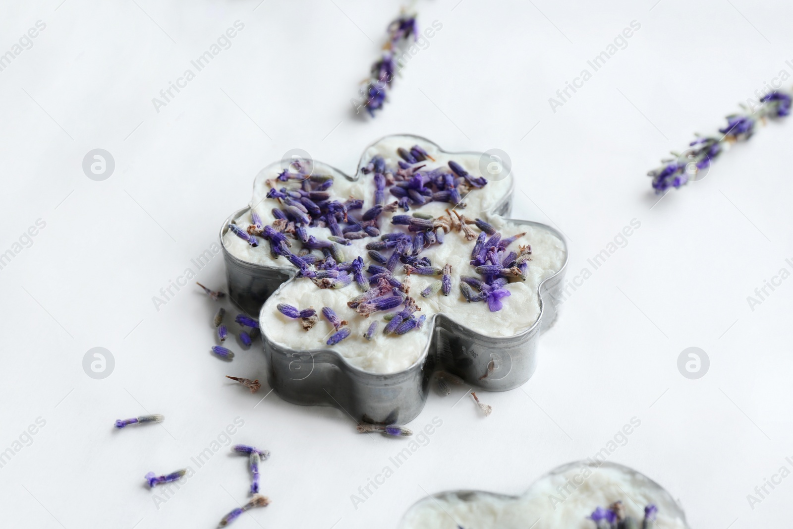 Photo of Handmade soap bar with lavender flowers in metal form on white paper, closeup