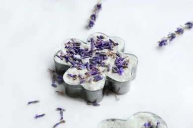 Handmade soap bar with lavender flowers in metal form on white paper, closeup