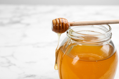 Photo of Tasty honey on light table, closeup. Space for text