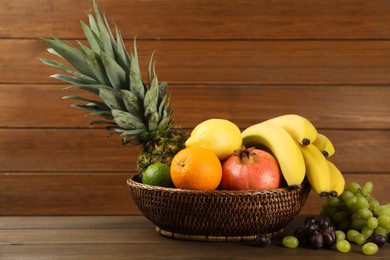 Photo of Wicker bowl with different ripe fruits on wooden table