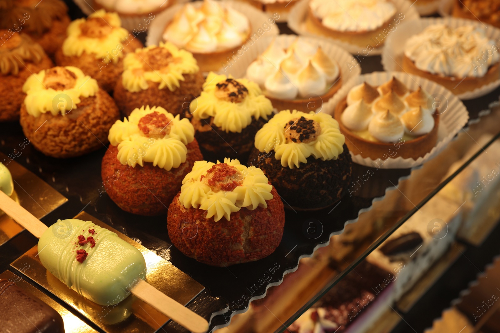 Photo of Different tasty desserts on counter in bakery shop, closeup