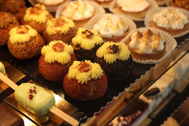 Photo of Different tasty desserts on counter in bakery shop, closeup