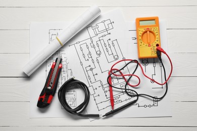 Wiring diagrams, wires and digital multimeter on white wooden table, flat lay