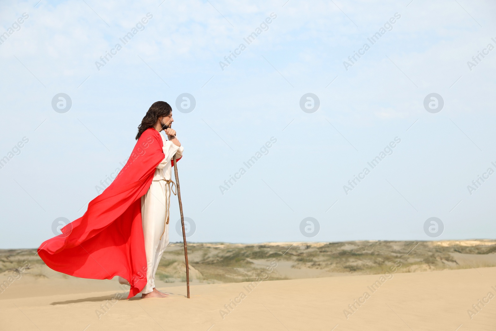 Photo of Jesus Christ walking with stick in desert. Space for text