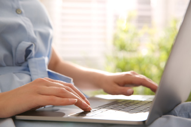 Photo of Woman working with modern laptop indoors, closeup