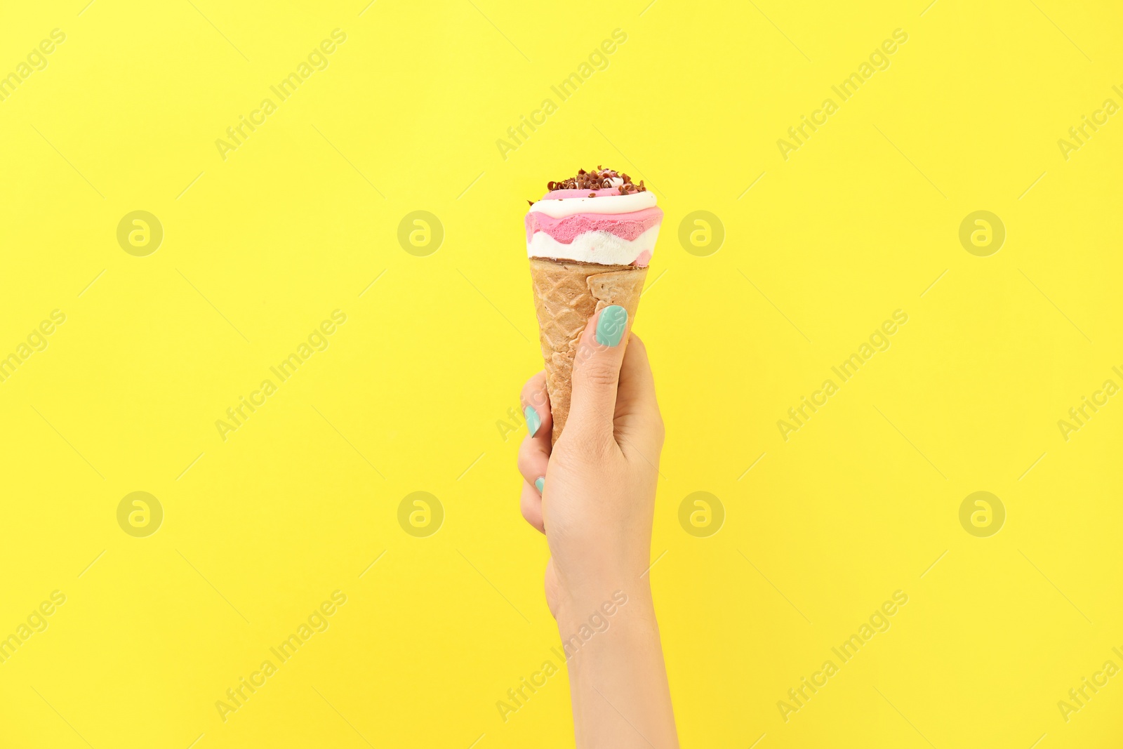 Photo of Woman holding yummy ice cream on color background. Focus on hand