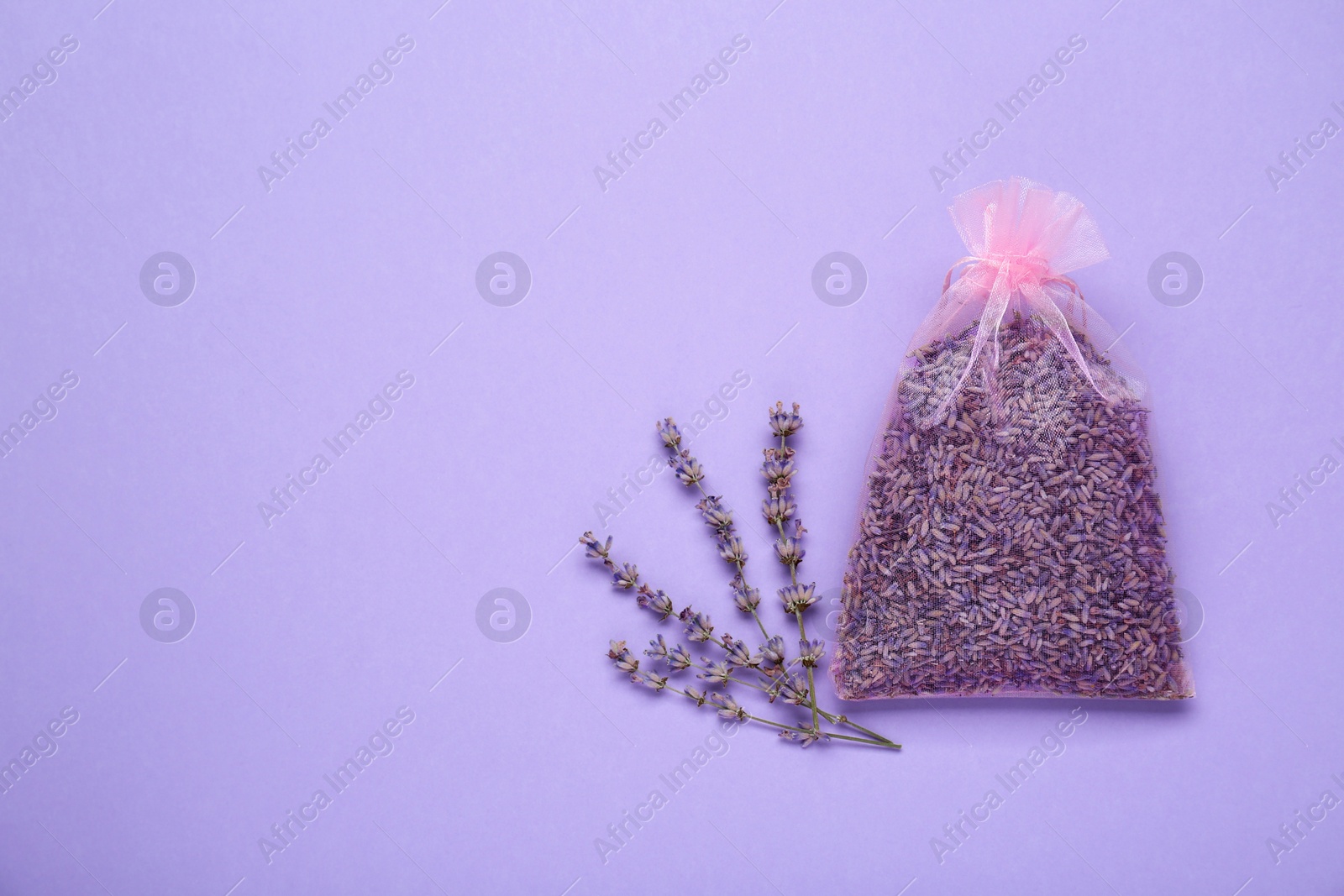 Photo of Scented sachet with dried lavender flowers on lilac background, flat lay. Space for text
