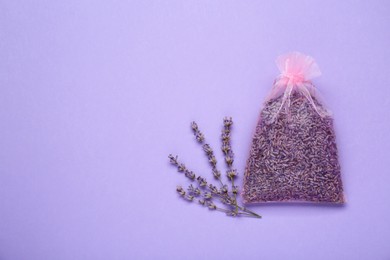 Scented sachet with dried lavender flowers on lilac background, flat lay. Space for text