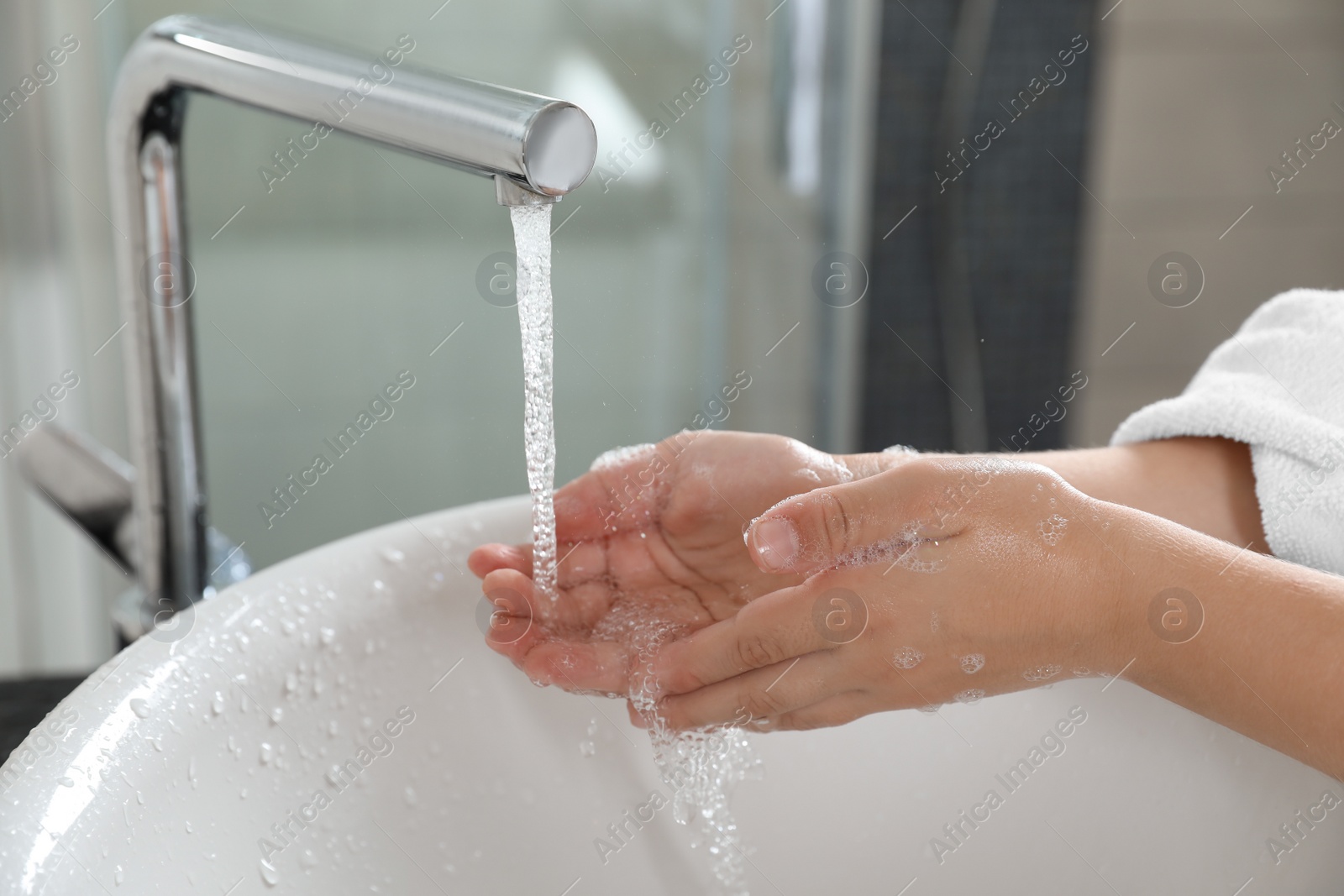 Photo of Little boy washing hands with soap over sink in bathroom, closeup