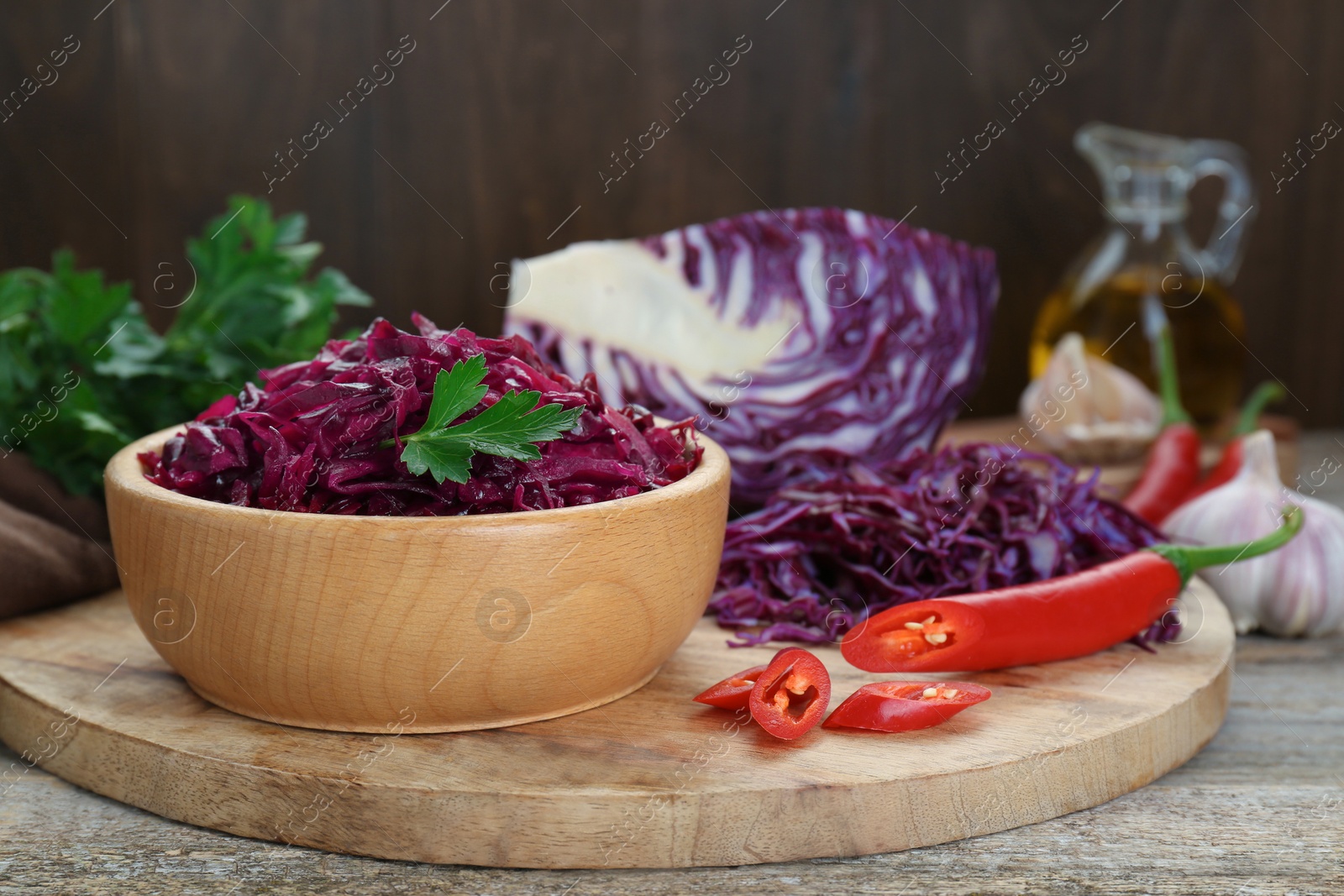 Photo of Tasty red cabbage sauerkraut and ingredients on wooden table