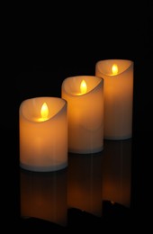 Photo of Glowing decorative LED candles on black background