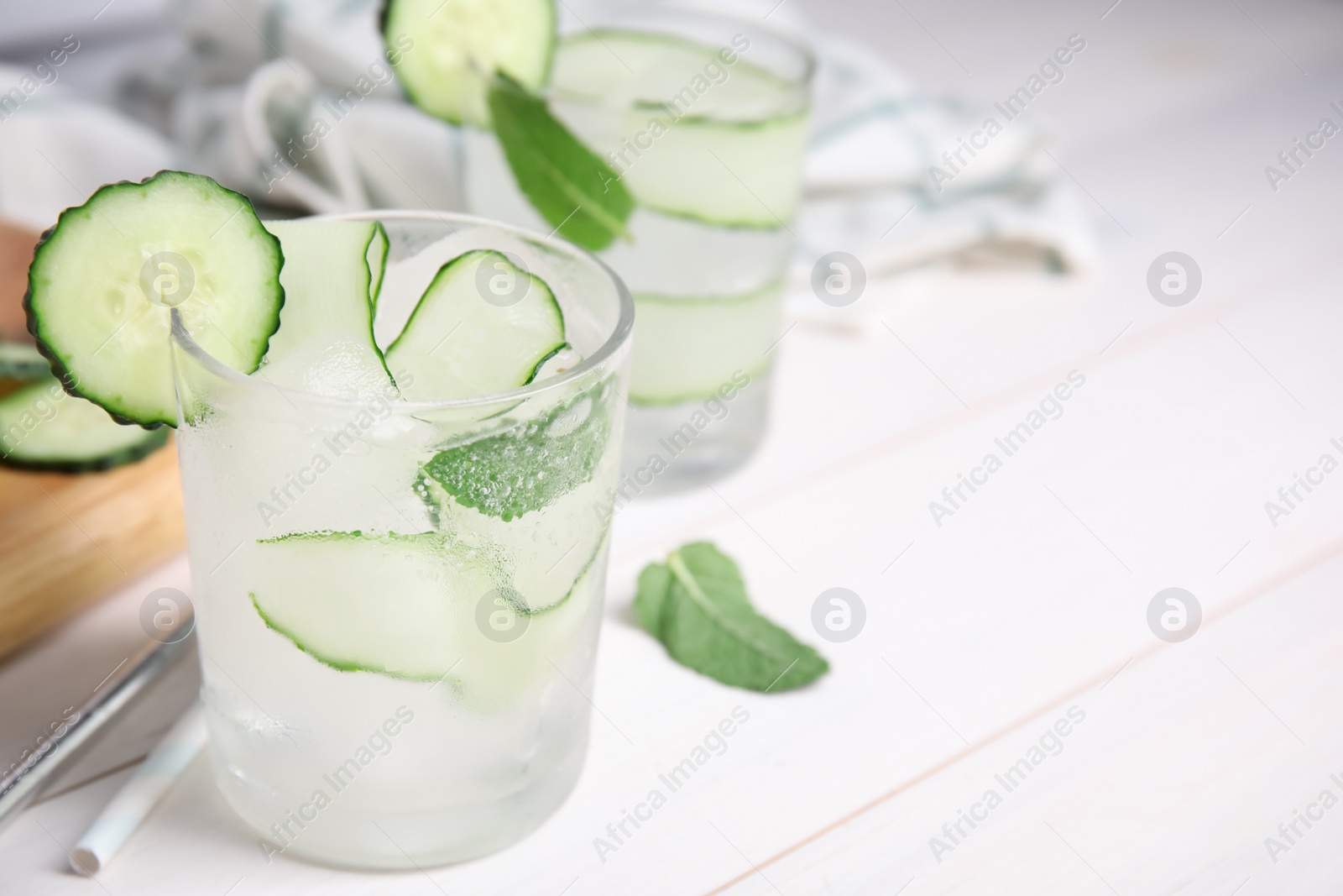 Photo of Tasty fresh cucumber water with mint on white wooden table, closeup. Space for text