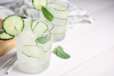 Photo of Tasty fresh cucumber water with mint on white wooden table, closeup. Space for text