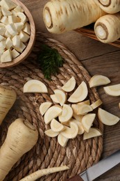 Whole and cut parsnips on wooden table, flat lay