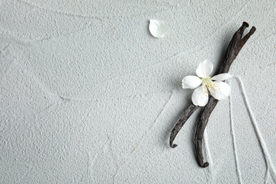 Photo of Flat lay composition with aromatic vanilla sticks and flower on light background, space for text