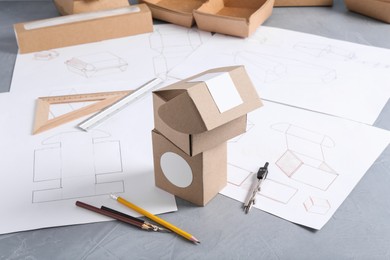 Photo of Creating packaging design. Drawings, boxes and stationery on blue textured table, closeup