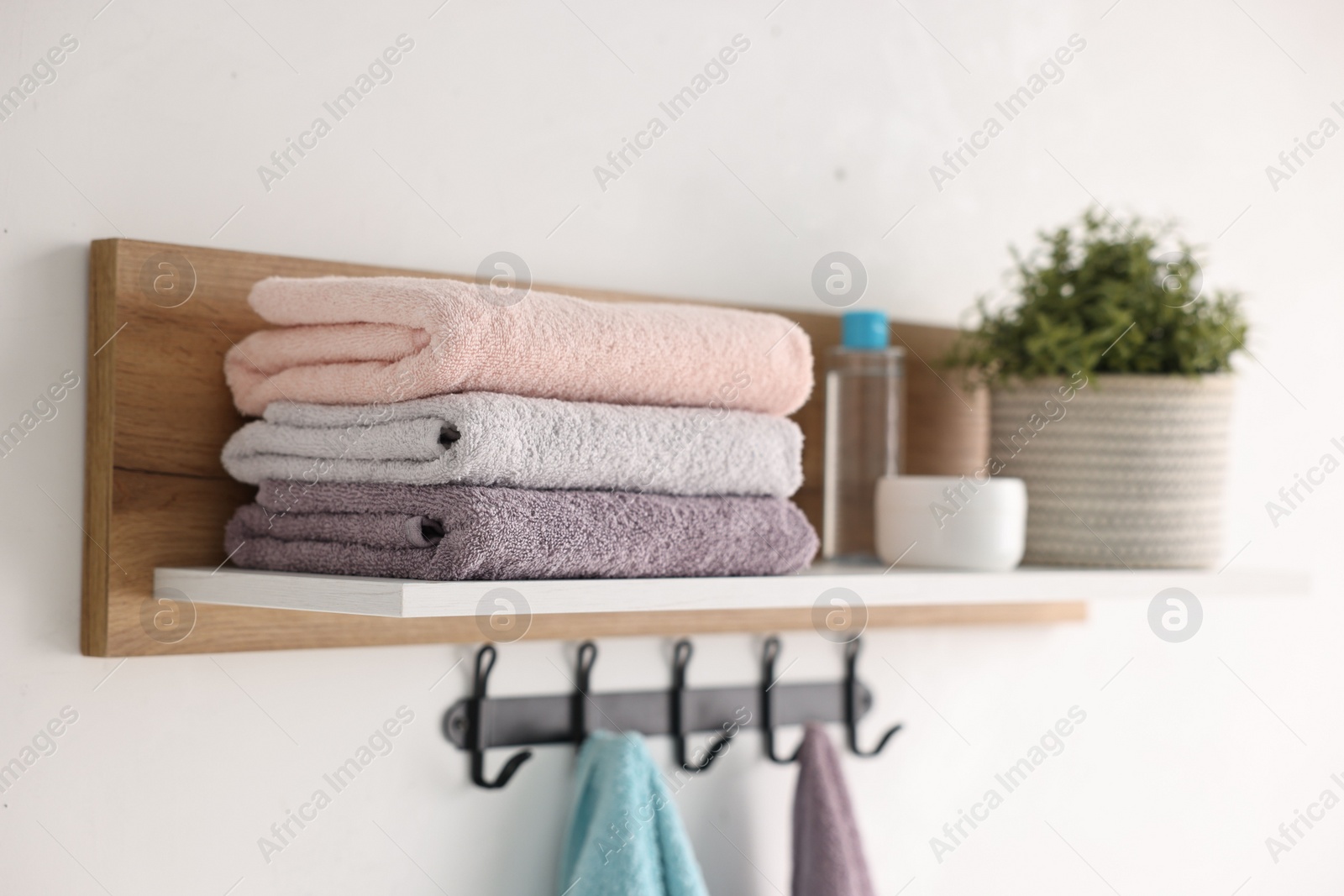 Photo of Clean towels, houseplant and toiletries on shelf indoors