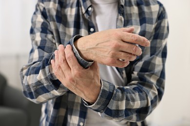 Photo of Arthritis symptoms. Man suffering from pain in wrist at home, closeup