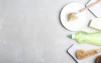 Photo of Flat lay composition with cleaning product and tools on grey table, space for text. Dish washing supplies