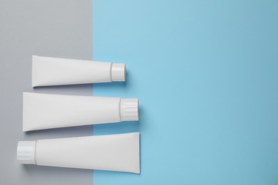 Photo of Blank tubes of toothpaste on color background, flat lay. Space for text